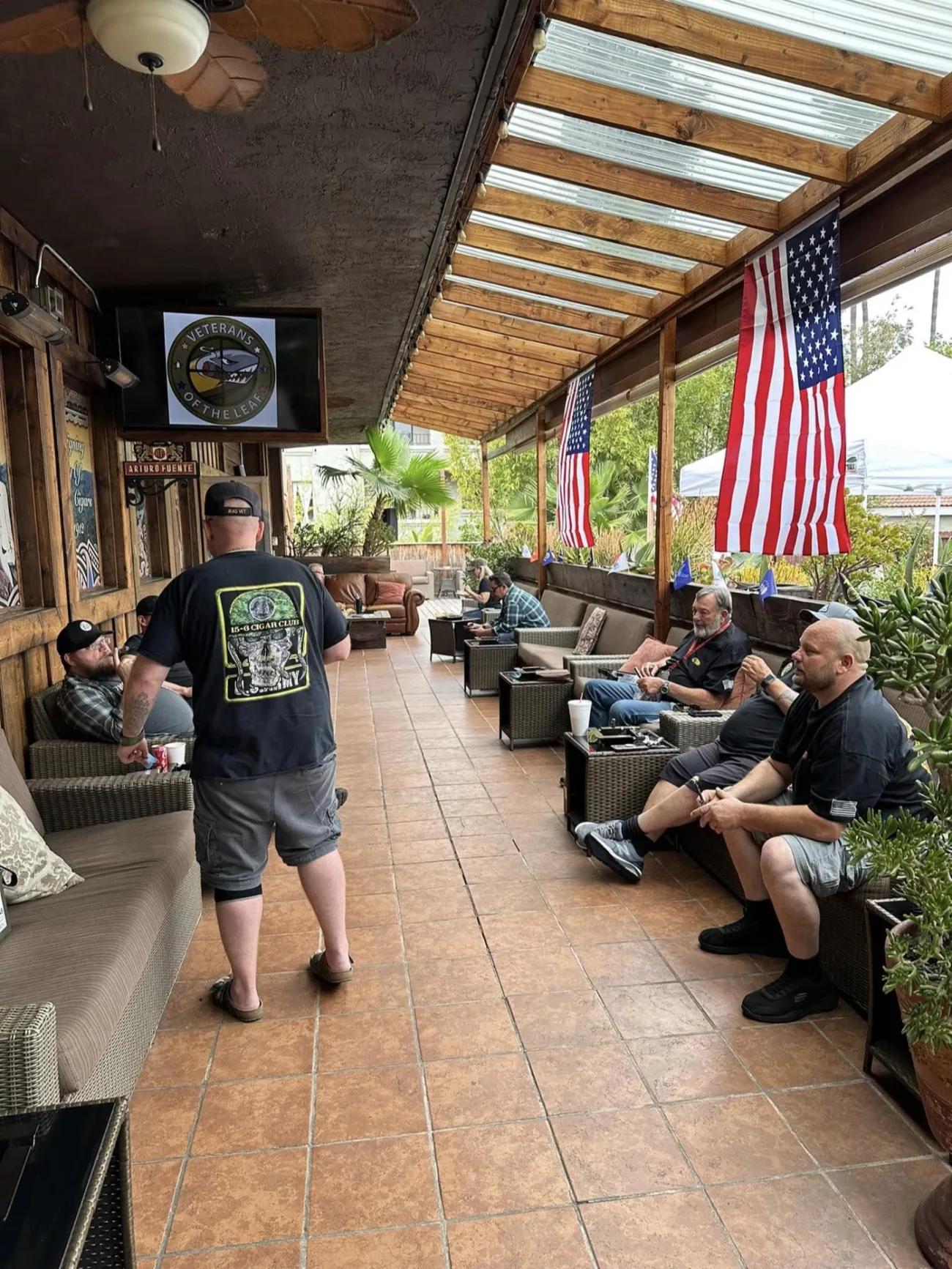 Regulars hanging out on the covered patio at Lord Puffer, under the skylight roof with American flags hanging along the rail