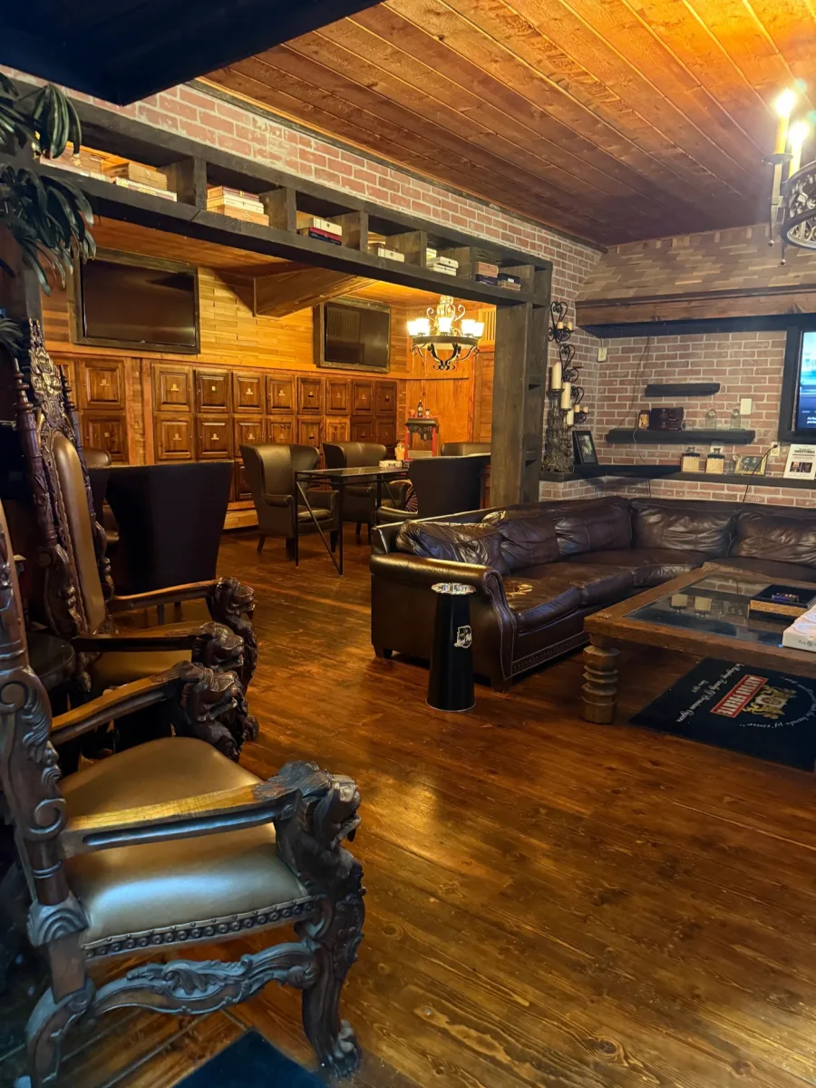 Inside the private lounge at Lord Puffer, with carved leather armchairs, wall-mounted humidor lockers, and a leather sectional couch